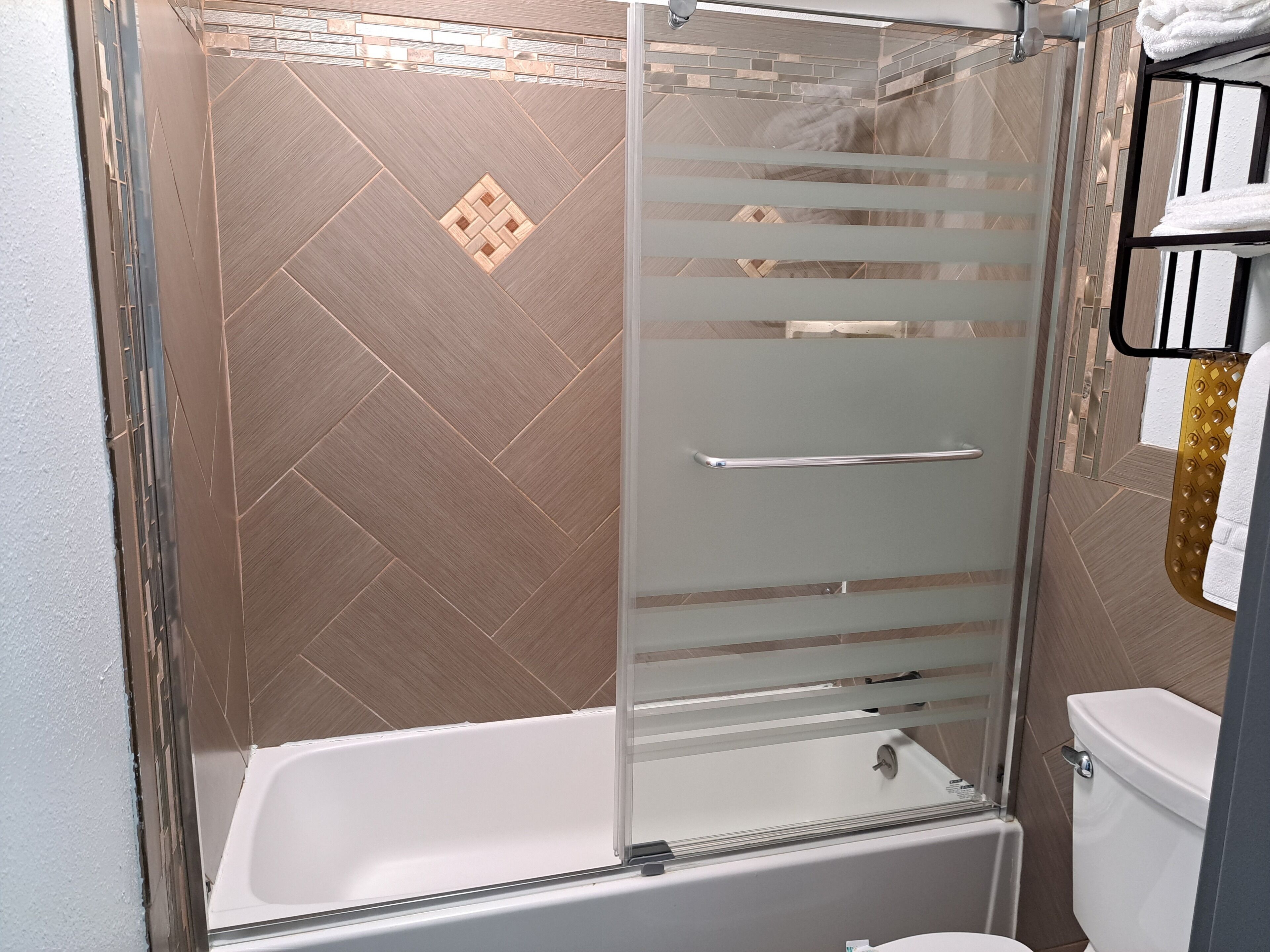A modern bathroom with a glass shower enclosure, a white bathtub, and a toilet.