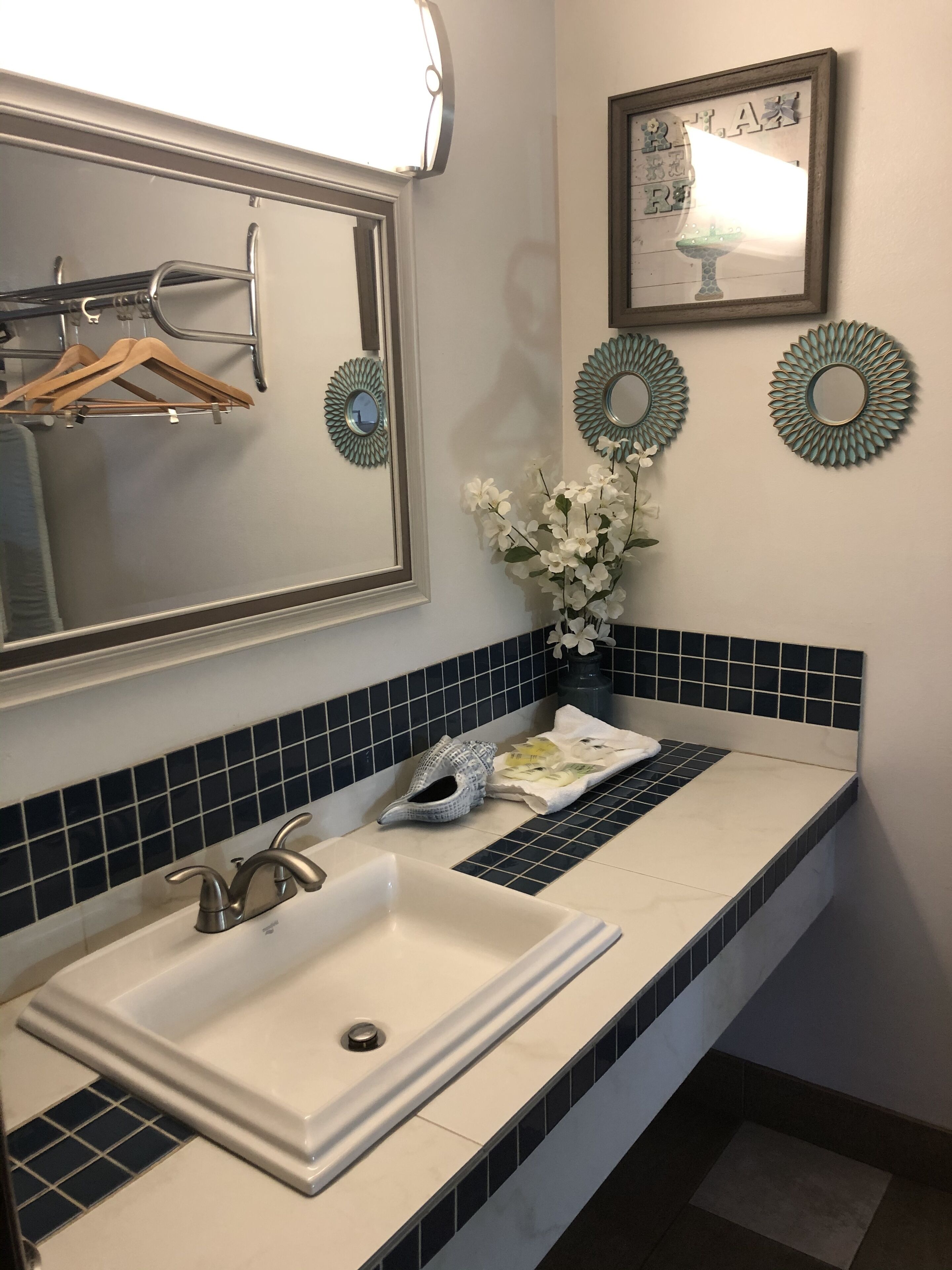 A bathroom with a white sink, blue-tiled backsplash, and decorative mirrors.