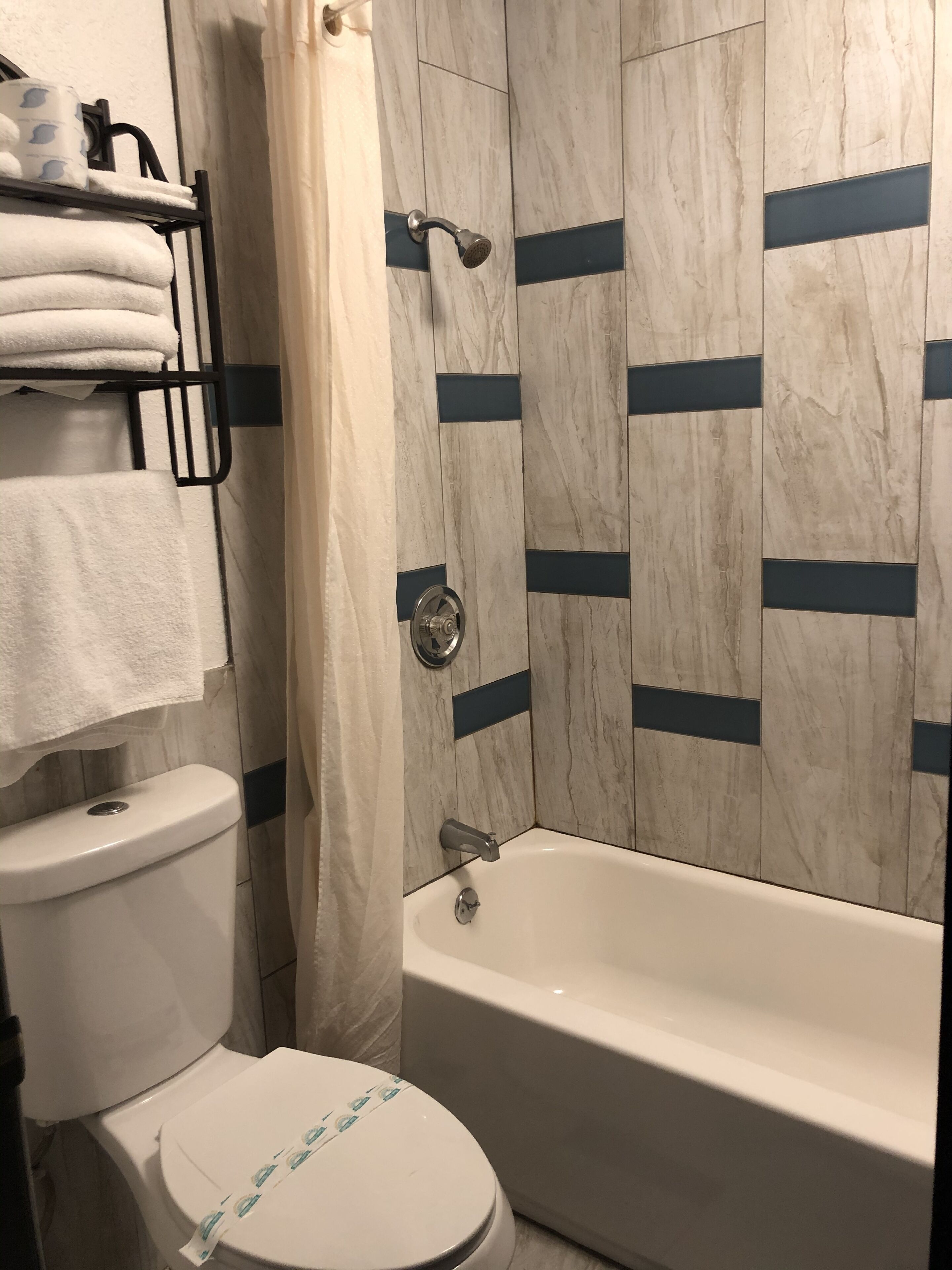 Un baño con inodoro, bañera y toallero con toallas.