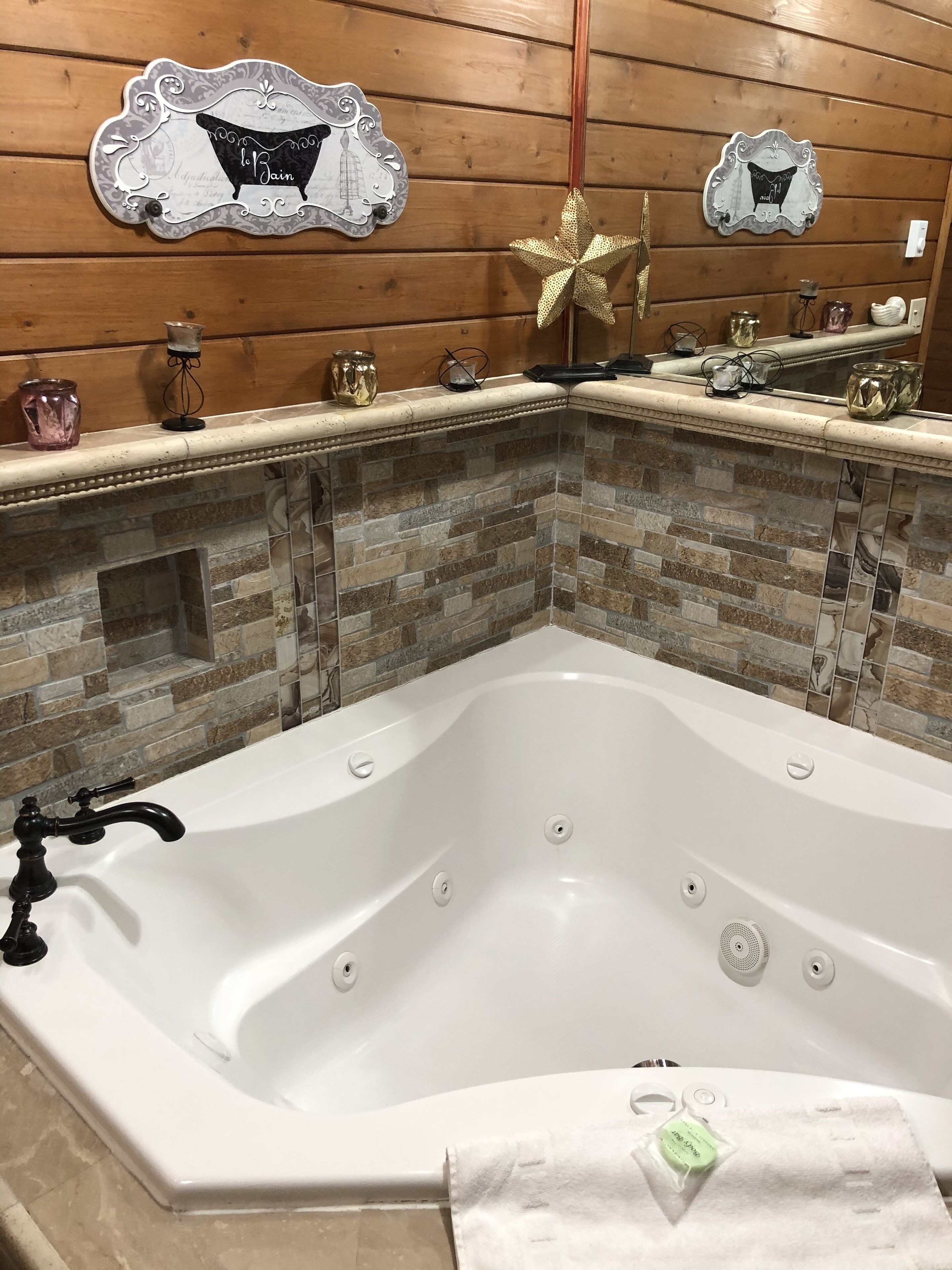 Une salle de bain moderne avec une baignoire sur pieds, des carreaux de mosaïque en pierre et des œuvres d’art décoratives murales.
