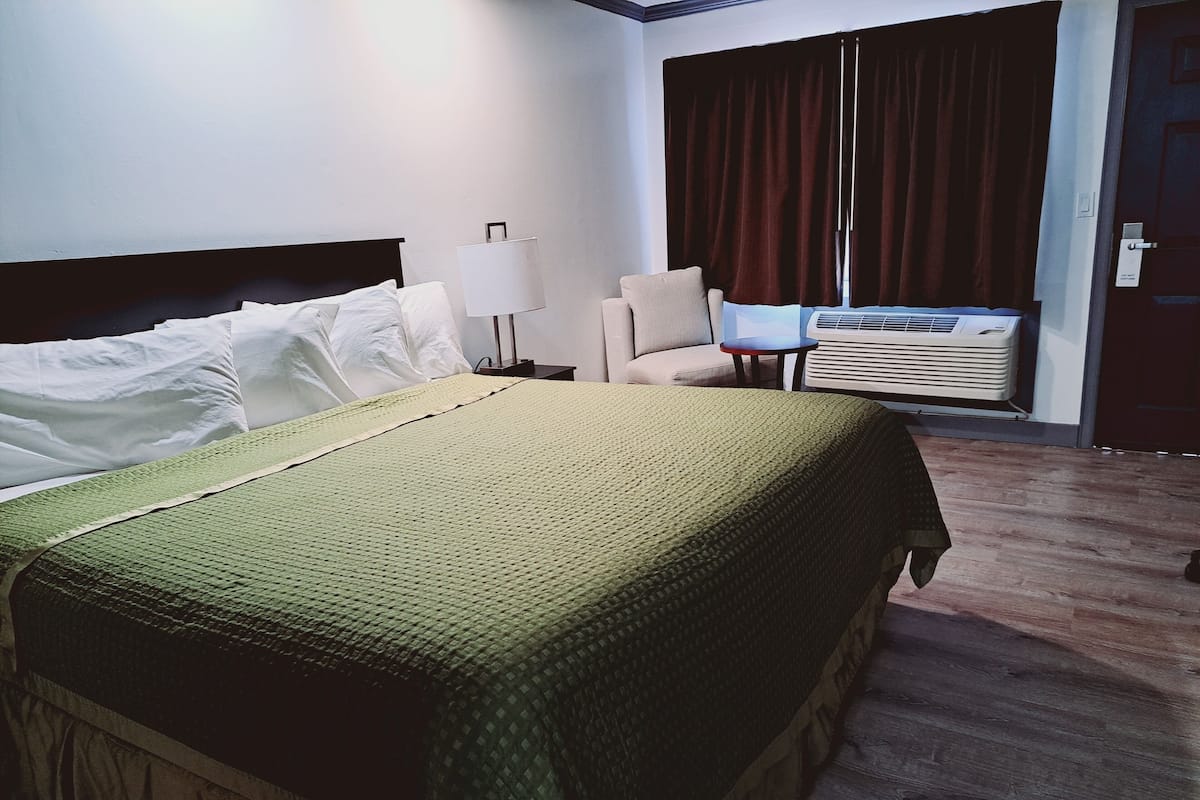 Une chambre d’hôtel équipée d’un lit, d’une chaise, d’une lampe et d’un appareil de climatisation.