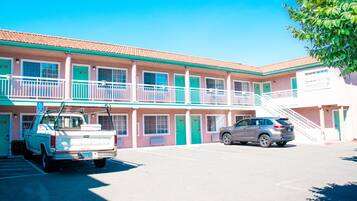 A motel with a two-story structure, a parking lot, and a staircase leading to the upper level.