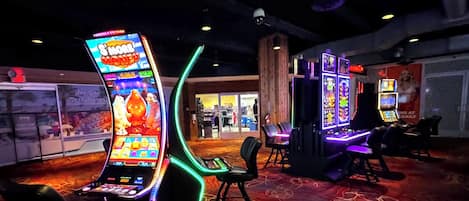 A gaming area with slot machines and a neon-lit arcade machine.