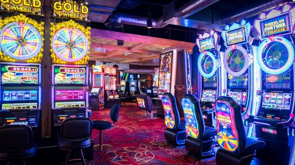 A casino with multiple slot machines and a vibrant, colorful carpet.