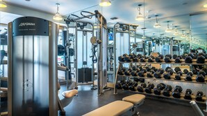 Une salle de sport équipée de divers appareils d’exercice, notamment des haltères et une machine pour les exercices des épaules.