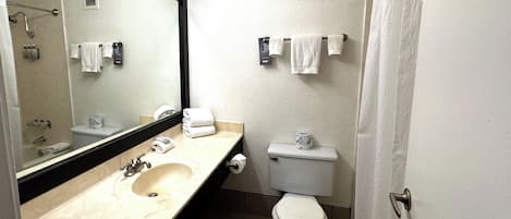 A bathroom with a sink, mirror, toilet, and towel rack.