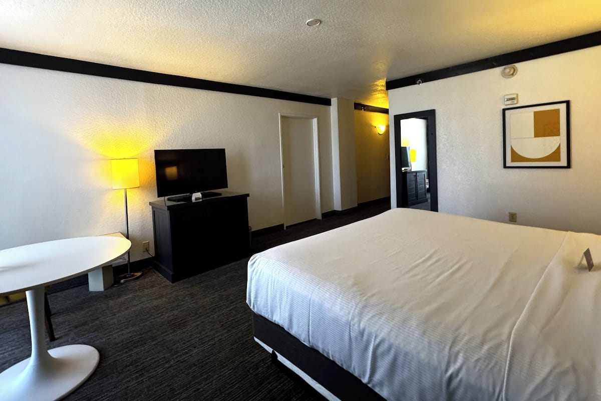 A hotel room with a bed, a desk, a television, and a dresser.