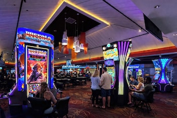 A hotel room with a large bed, a round mirror, a nightstand, and a desk with a lamp. at OYO Hotel and Casino Las Vegas
