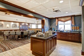 A spacious hotel lobby with a large dining area, a kitchen counter, and a seating area with tables and chairs. - Homewood Suites by Hilton Toronto Oakville (Oakville)