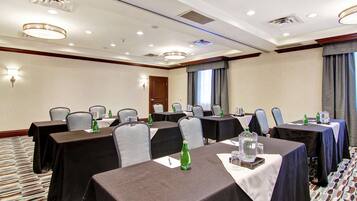 Un salón de conferencias con mesas dispuestas para reuniones, equipado con botellas de agua y blocs de notas.