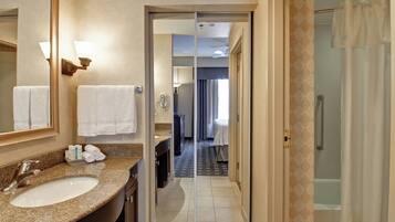 A hotel bathroom with a sink, mirror, and towel rack.