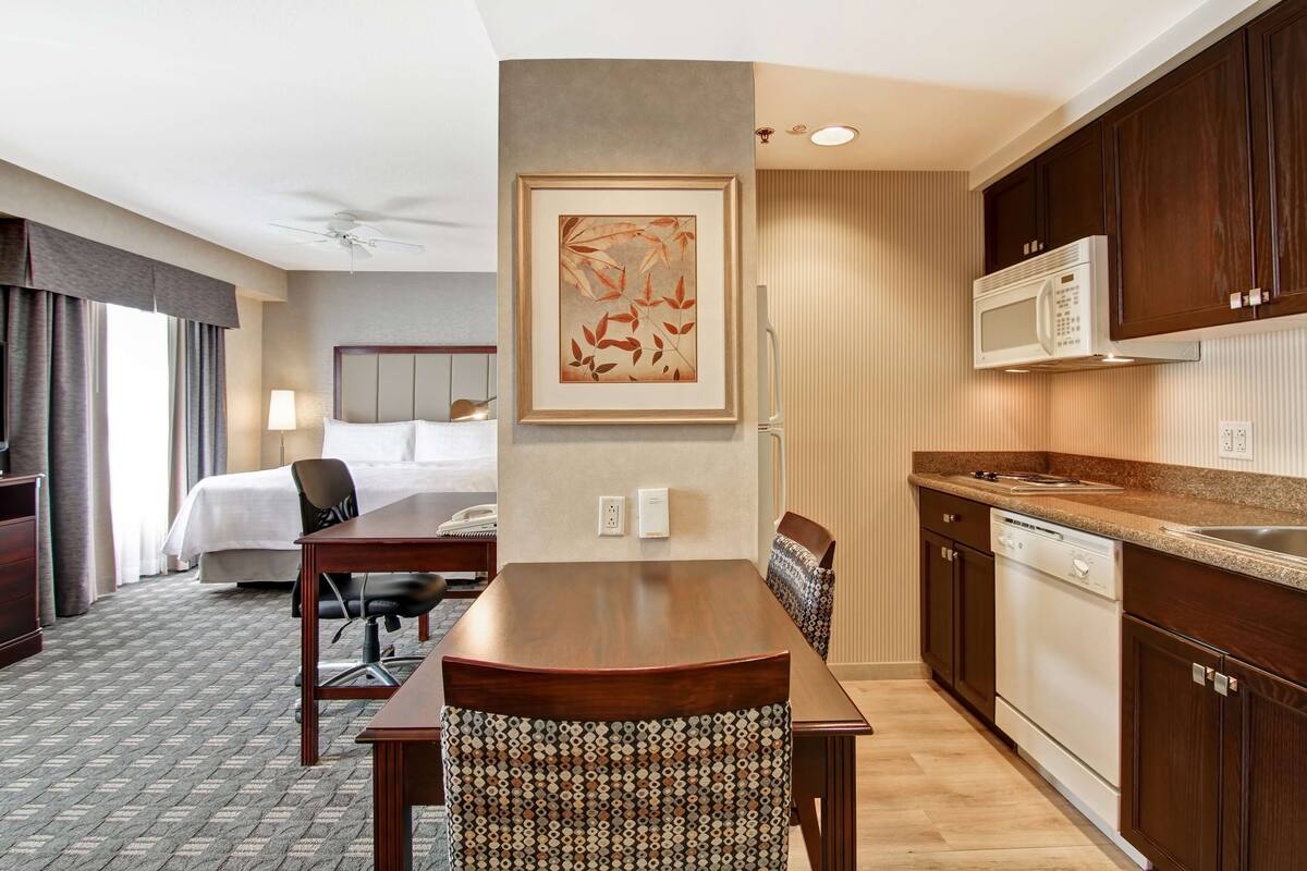Une chambre d’hôtel équipée d’un lit, d’un bureau, d’une chaise, d’un four à micro-ondes et d’un lave-vaisselle.
