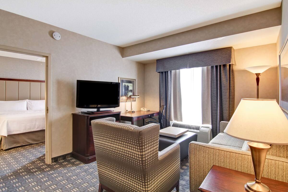 Une chambre d’hôtel comprenant un lit, une télévision, un bureau avec une lampe et une chaise.