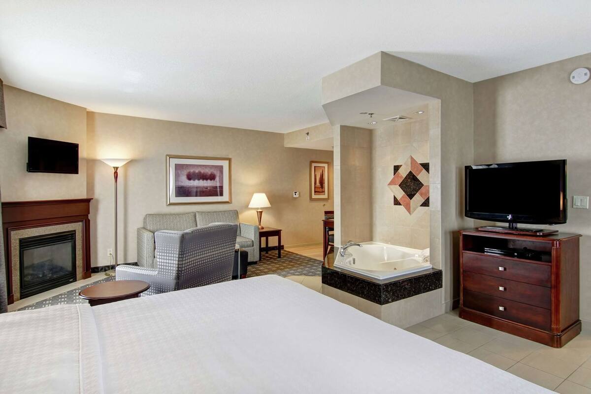 Une chambre d’hôtel équipée d’un lit, d’une télévision, d’une cheminée, d’un canapé, d’une lampe et d’une baignoire.