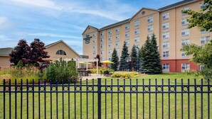 A hotel with a large building, outdoor seating area, and a fenced courtyard.