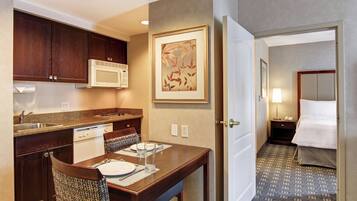 A hotel room with a kitchenette, a dining area, and a bed.