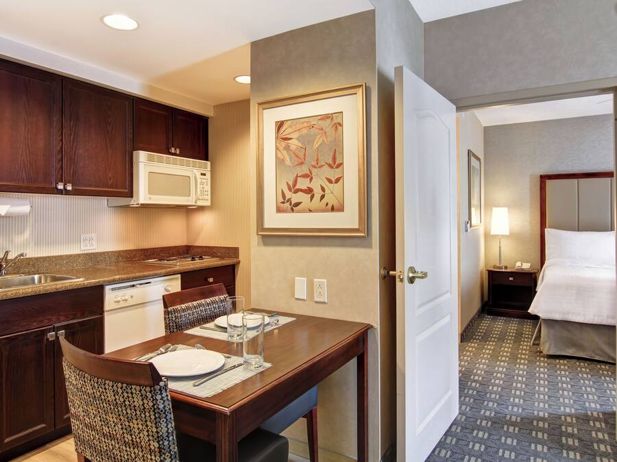 A hotel room with a kitchenette, a dining area, and a bed.