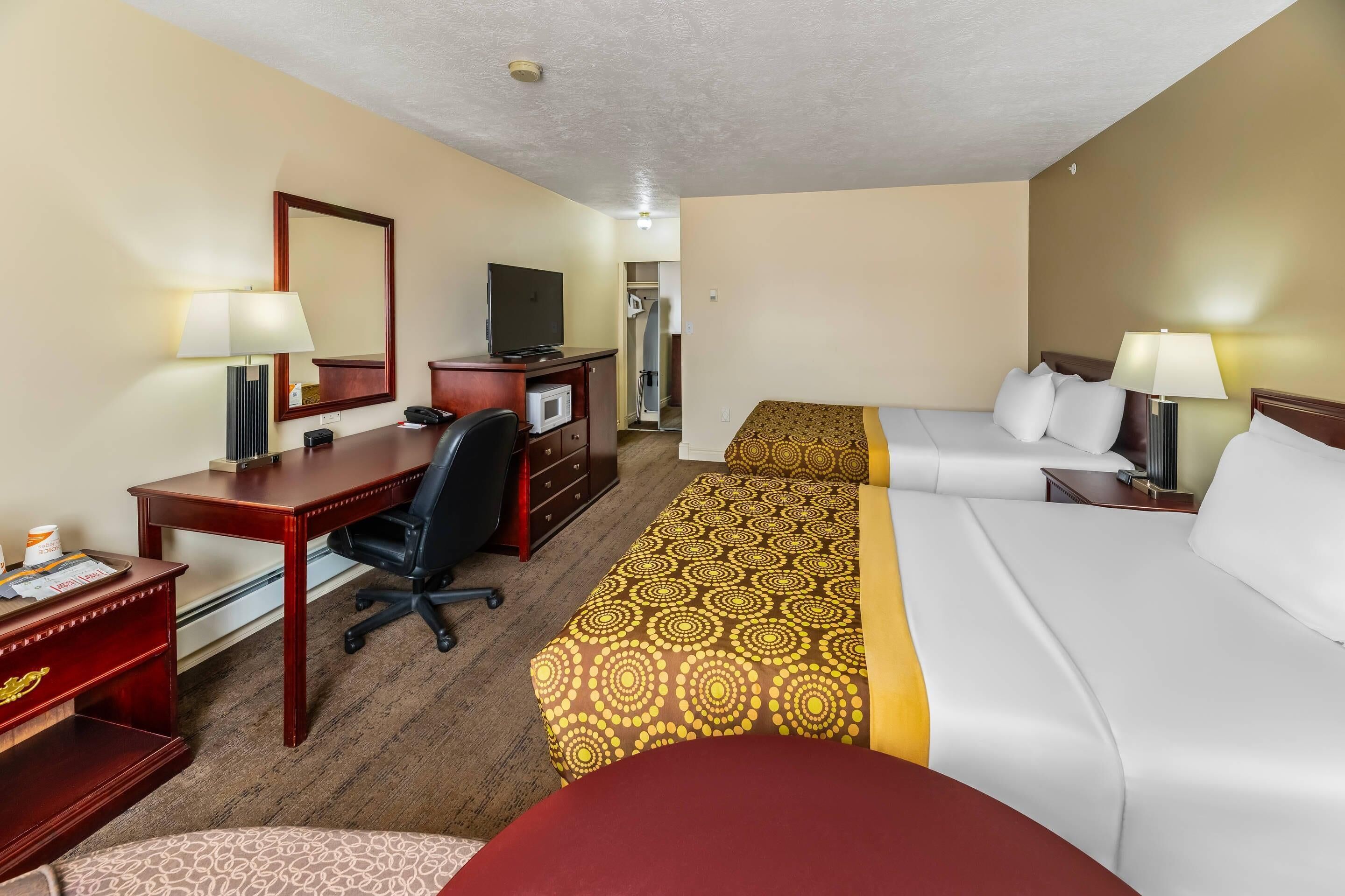 Habitación de hotel con escritorio, dos camas, televisión y armario.