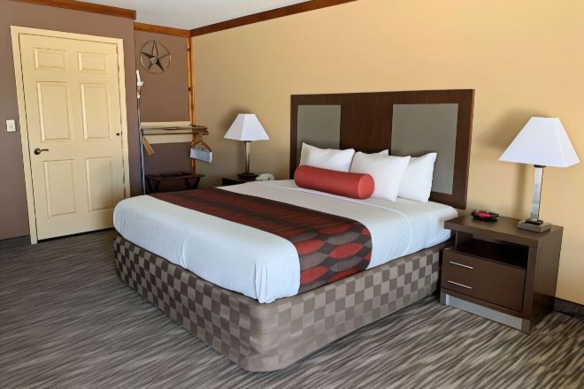 A hotel room with a large bed, two bedside tables, a desk, and a chair.