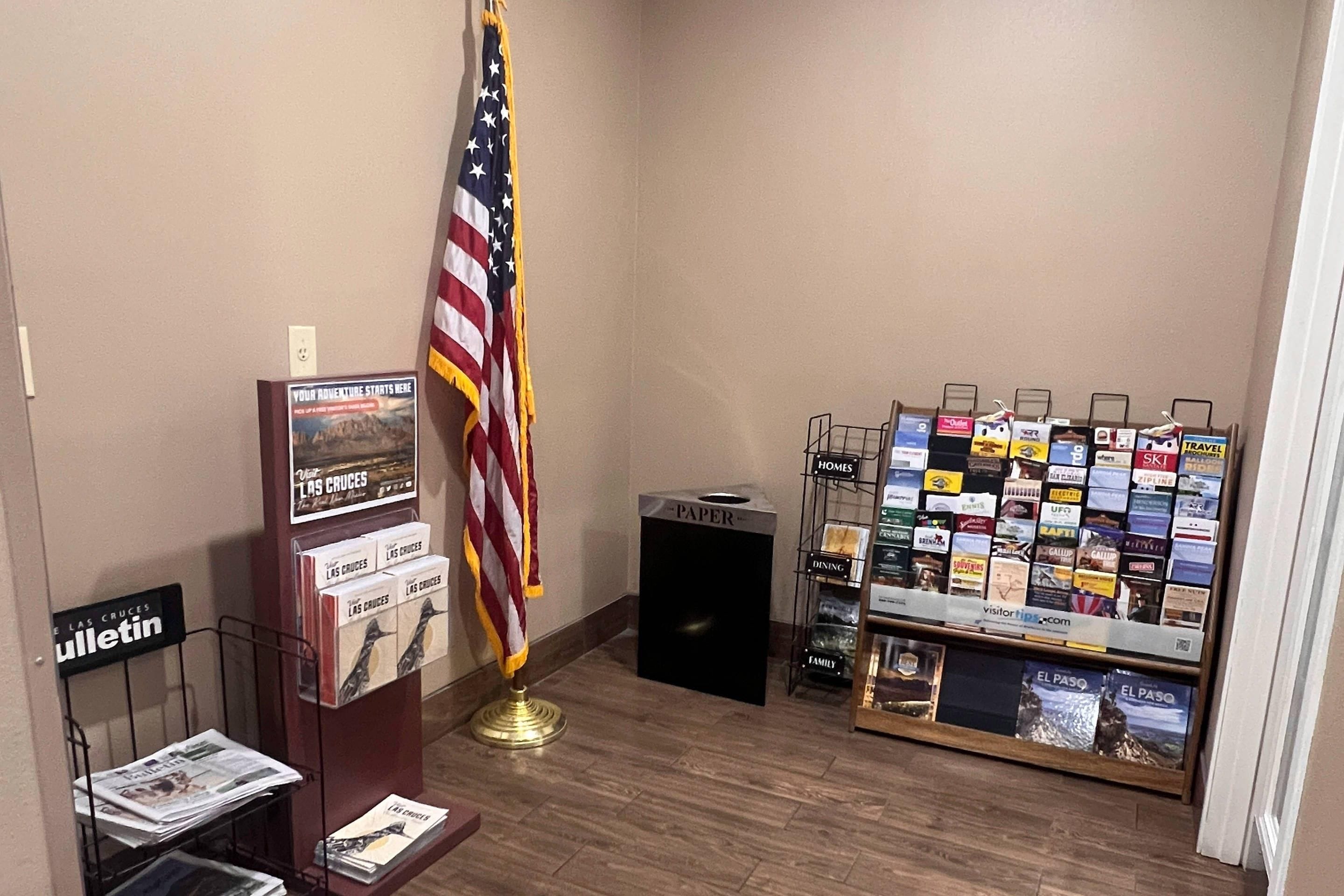 A bulletin board with travel brochures, a flag, and a paper recycling bin.
