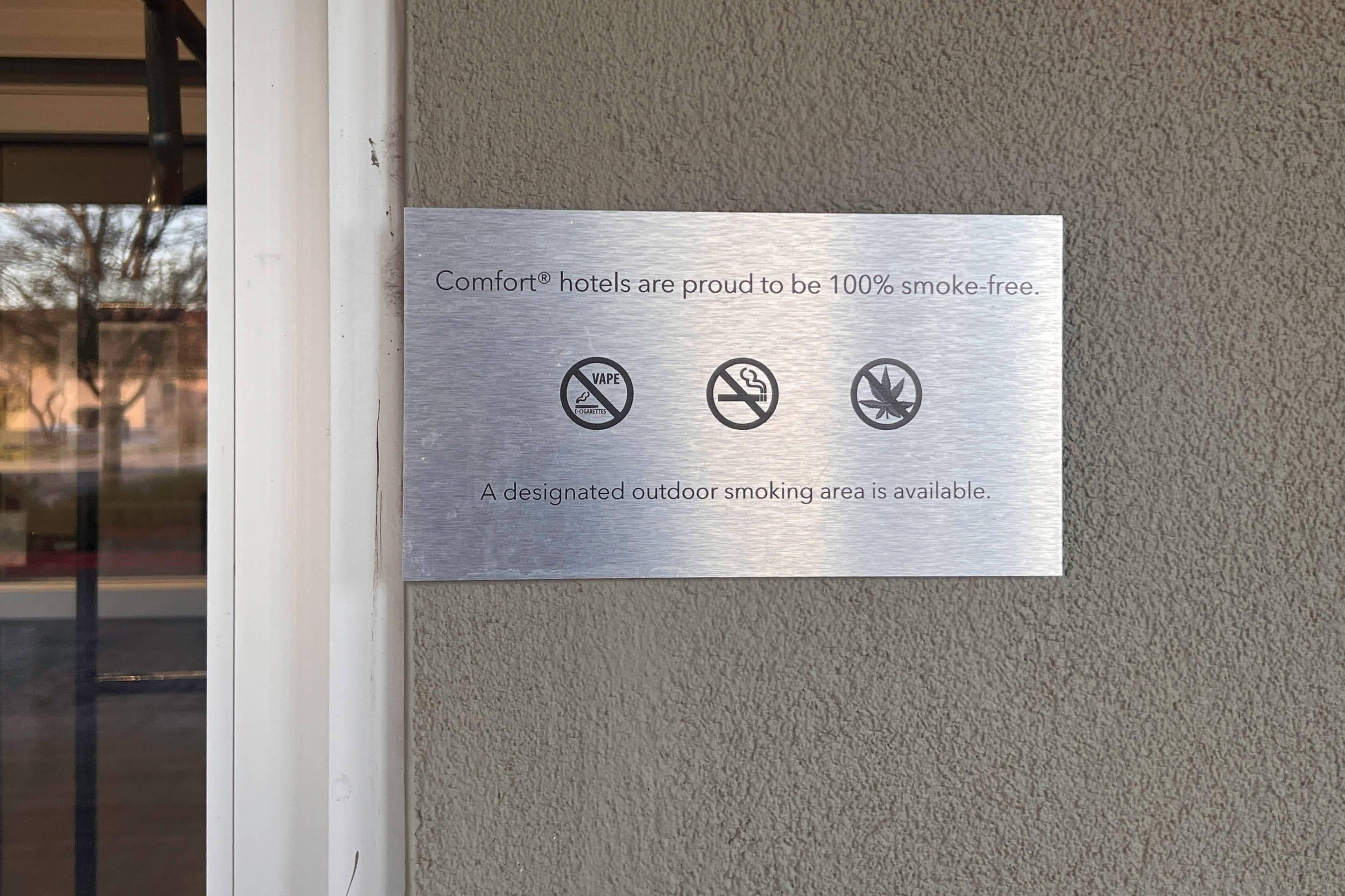 Une plaque métallique fixée au mur indique que tous les hôtels Comfort sont entièrement non-fumeurs et qu’un espace extérieur est réservé aux fumeurs.