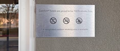 Una placa metálica en una pared indica que los hoteles Comfort son 100% libres de humo y cuentan con un área designada para fumadores al aire libre.