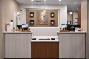 A reception desk with two computer monitors, a large wall-mounted logo, and a wooden reception desk. - Comfort Inn & Suites Las Cruces Mesilla (Las Cruces)