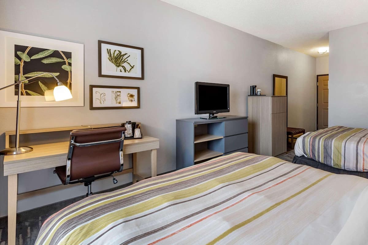 A hotel room with a bed, desk, chair, TV, and wardrobe.