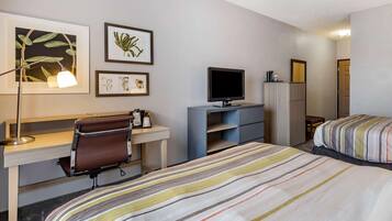 A hotel room with a bed, desk, chair, TV, and wardrobe.