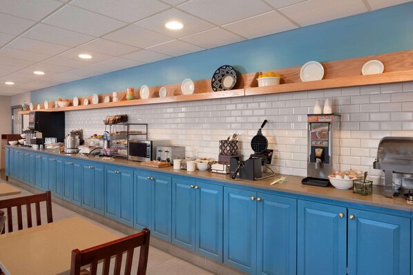 Une cuisine avec des meubles de rangement bleus, un coin café et divers appareils électroménagers.