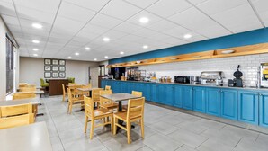 Un restaurant propre et moderne, avec des tables et des chaises en bois, un comptoir bleu et un sol carrelé.