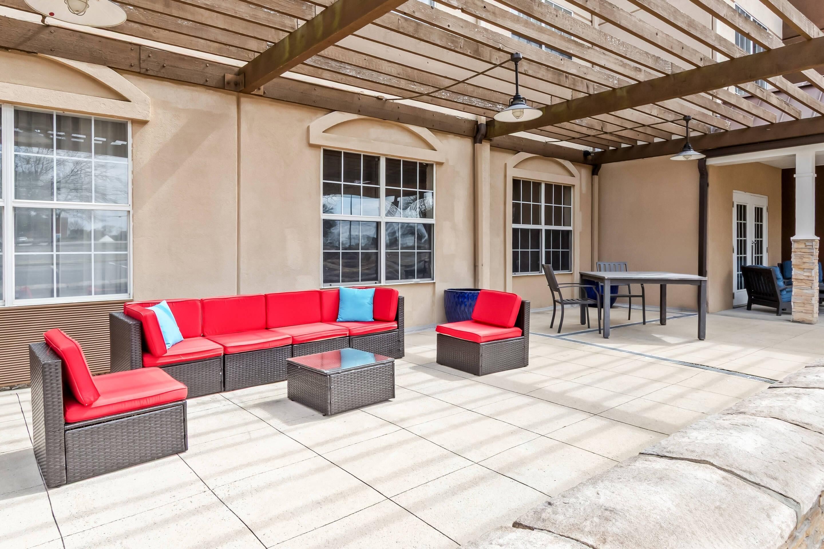 A covered patio area with wicker furniture, a table, and chairs.