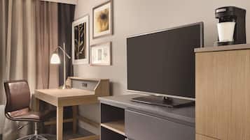 Una habitación de hotel con escritorio, silla, televisor y cafetera.