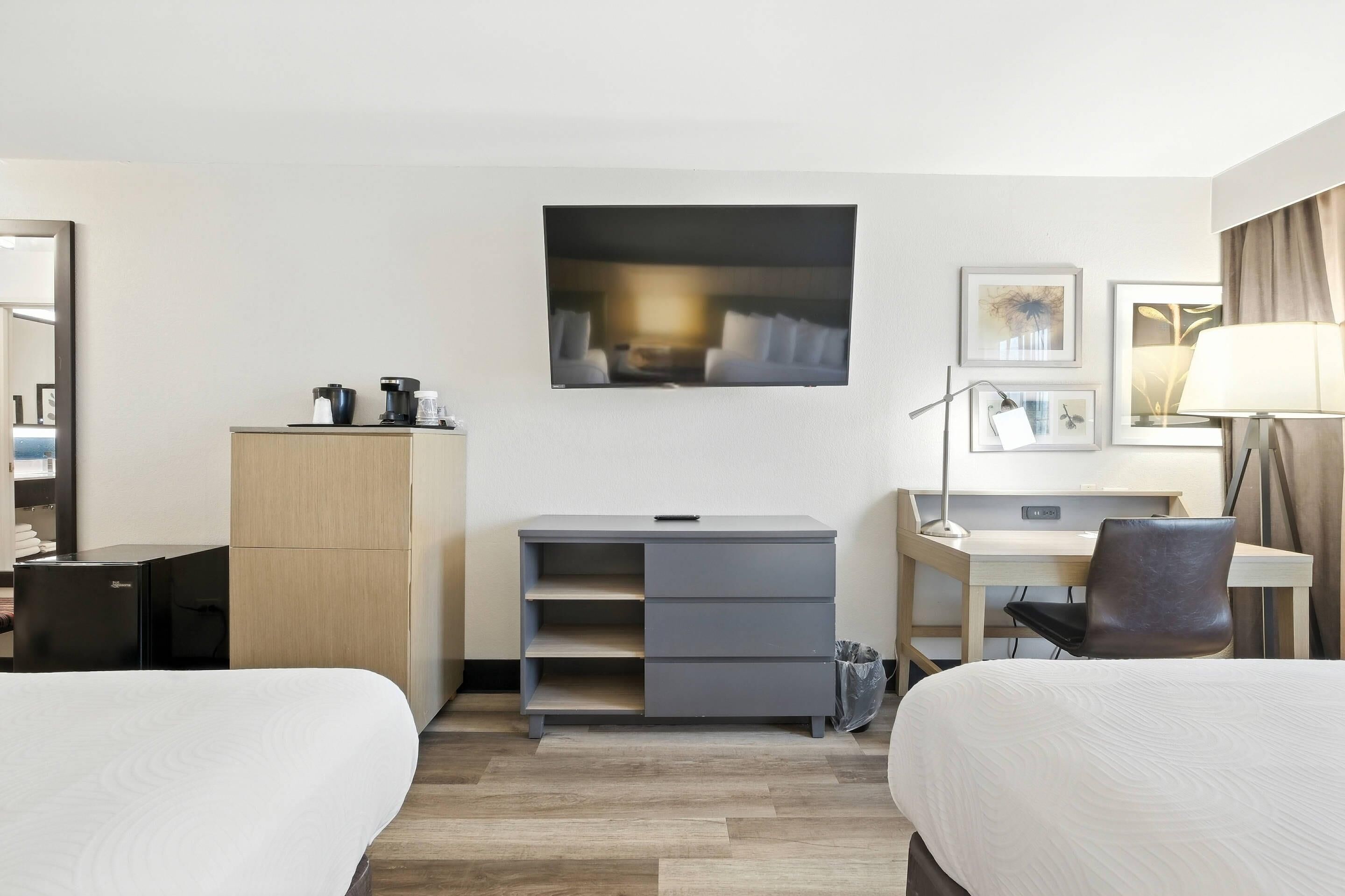 Ett hotellrum med två sängar, ett skrivbord, en stol, en garderob och en TV.