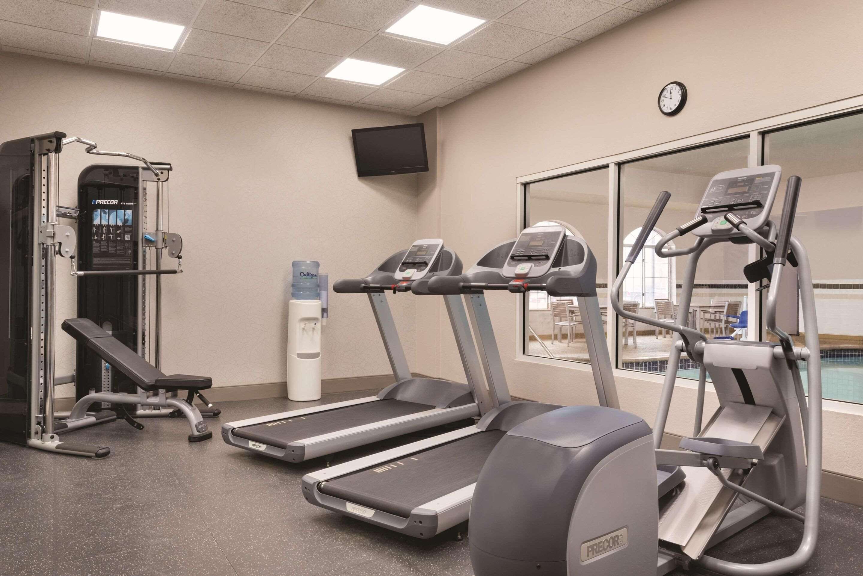 A gym with treadmills, a bench press, and a water dispenser.