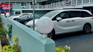 A motel with a white car parked in the lot, an American flag, and a sign for 'Morro Bay Beach Inn.' - Morro Bay Beach Inn (Morro Bay)