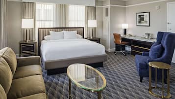 Habitación de hotel con una cama grande, un escritorio, una silla y una pequeña mesa.