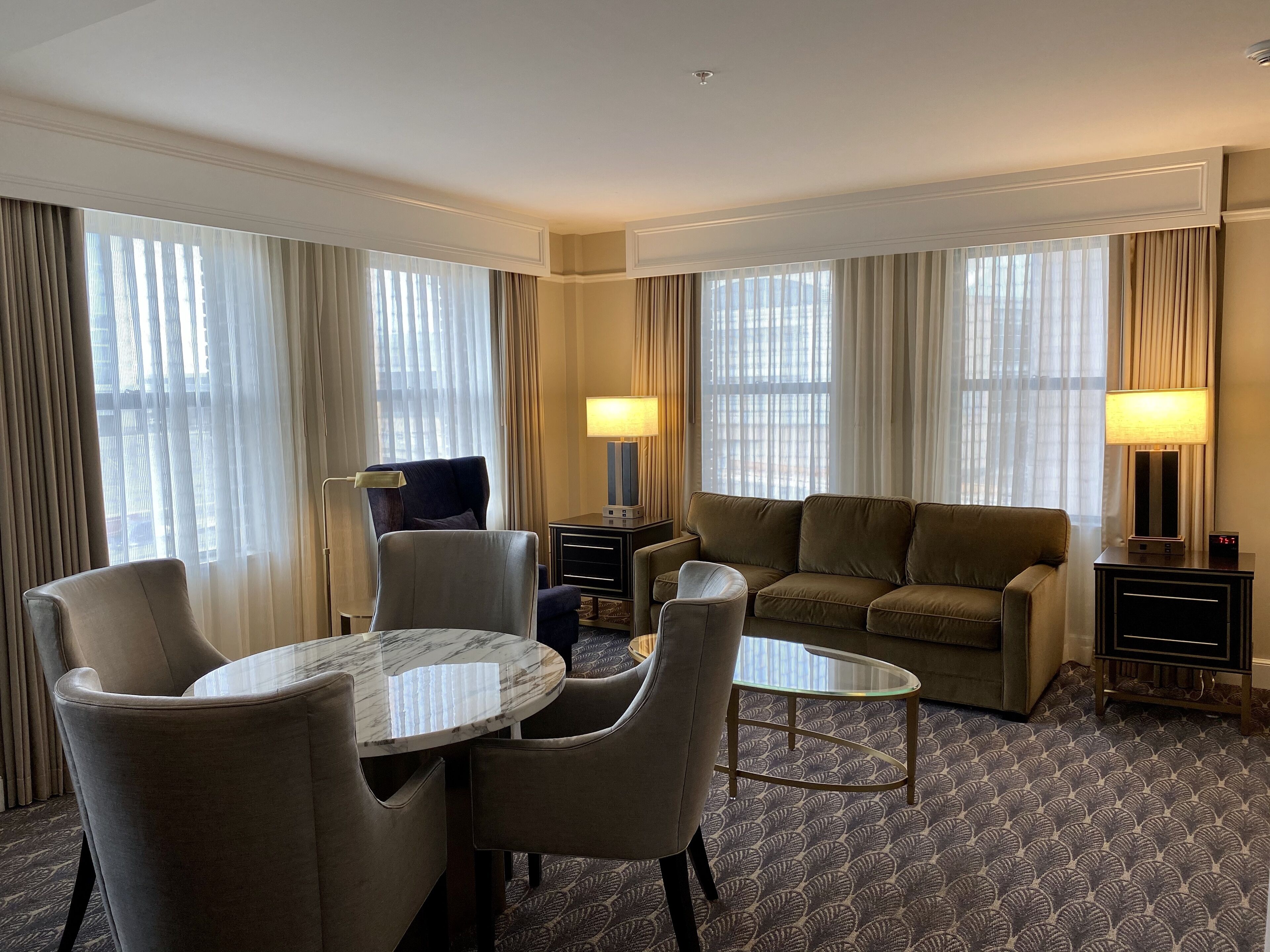 Habitación de hotel con una mesa de comedor, dos sillas, un sofá y una pequeña mesa de centro.