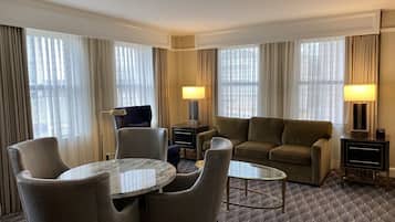 Habitación de hotel con una mesa de comedor, dos sillas, un sofá y una pequeña mesa de centro.