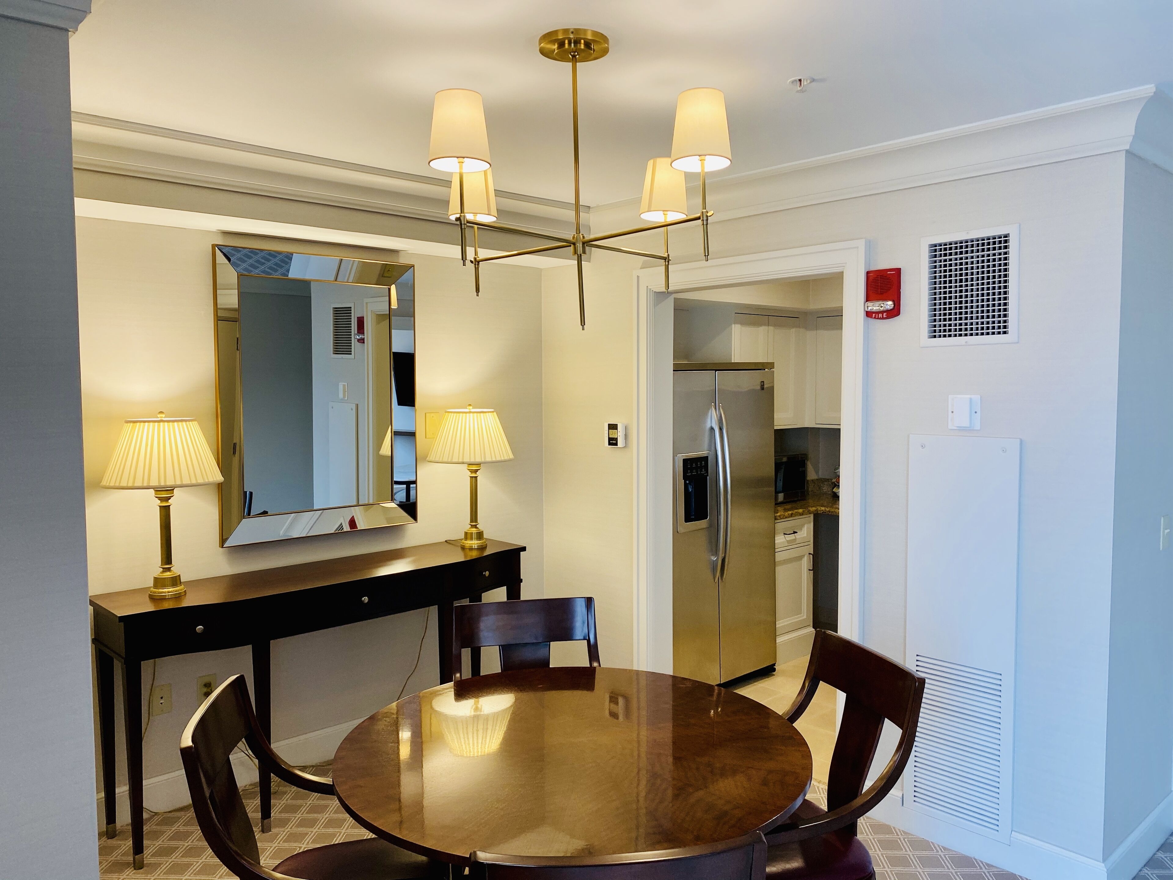 Un coin repas avec une table ronde, des chaises, un miroir et un lustre.
