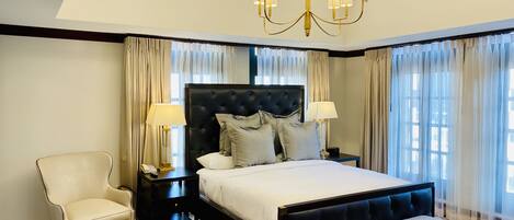 A large bed with a dark headboard, two bedside tables, a chair, and a bench.
