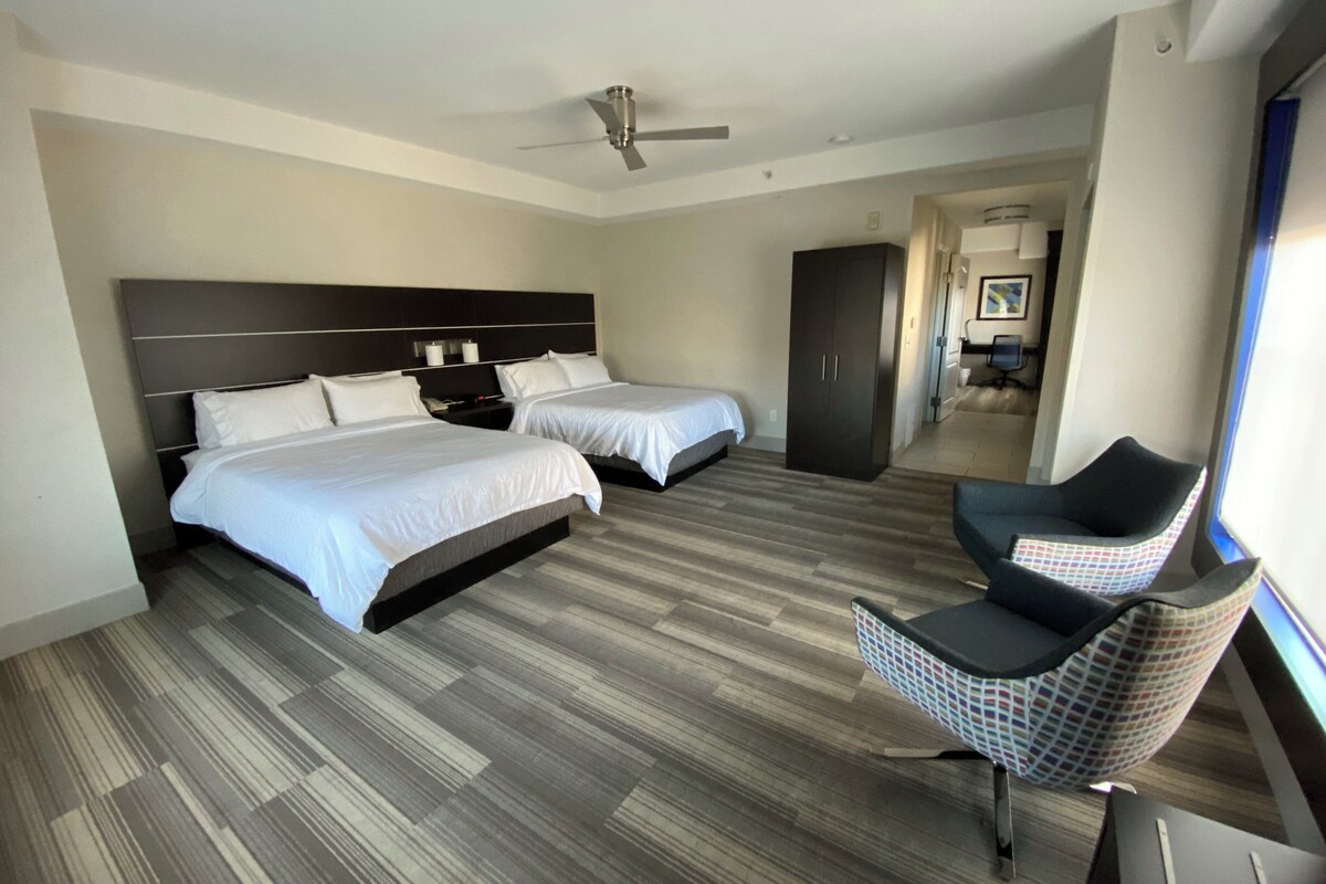 Una habitación de hotel con dos camas, un armario, un escritorio y una silla.