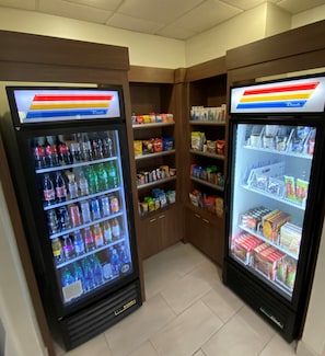 Dos máquinas expendedoras refrigeradas con estantes llenos de bebidas y aperitivos diversos.