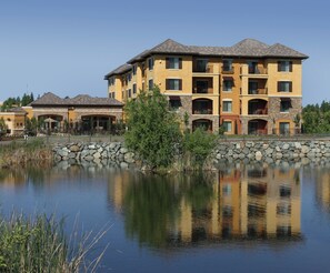 Un hôtel à plusieurs étages, doté d’une façade en pierre, de nombreux balcons et dont l’image se reflète dans l’eau.