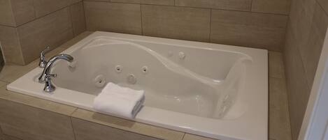 A modern bathroom with a rectangular bathtub, a single faucet, and a towel placed on the edge.