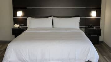 A large bed with a white bedspread, two bedside tables with lamps, and a dark headboard.