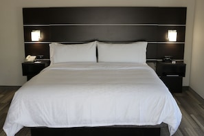 A large bed with a white bedspread, two bedside tables with lamps, and a dark headboard.