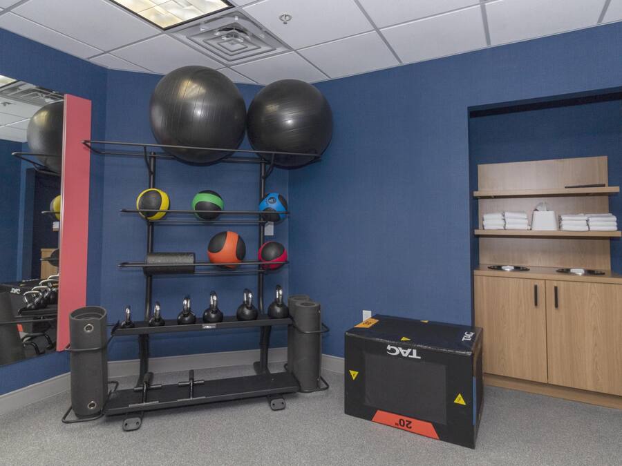 Une salle de sport équipée de matériel d’exercice, d’un miroir et d’un meuble de rangement.