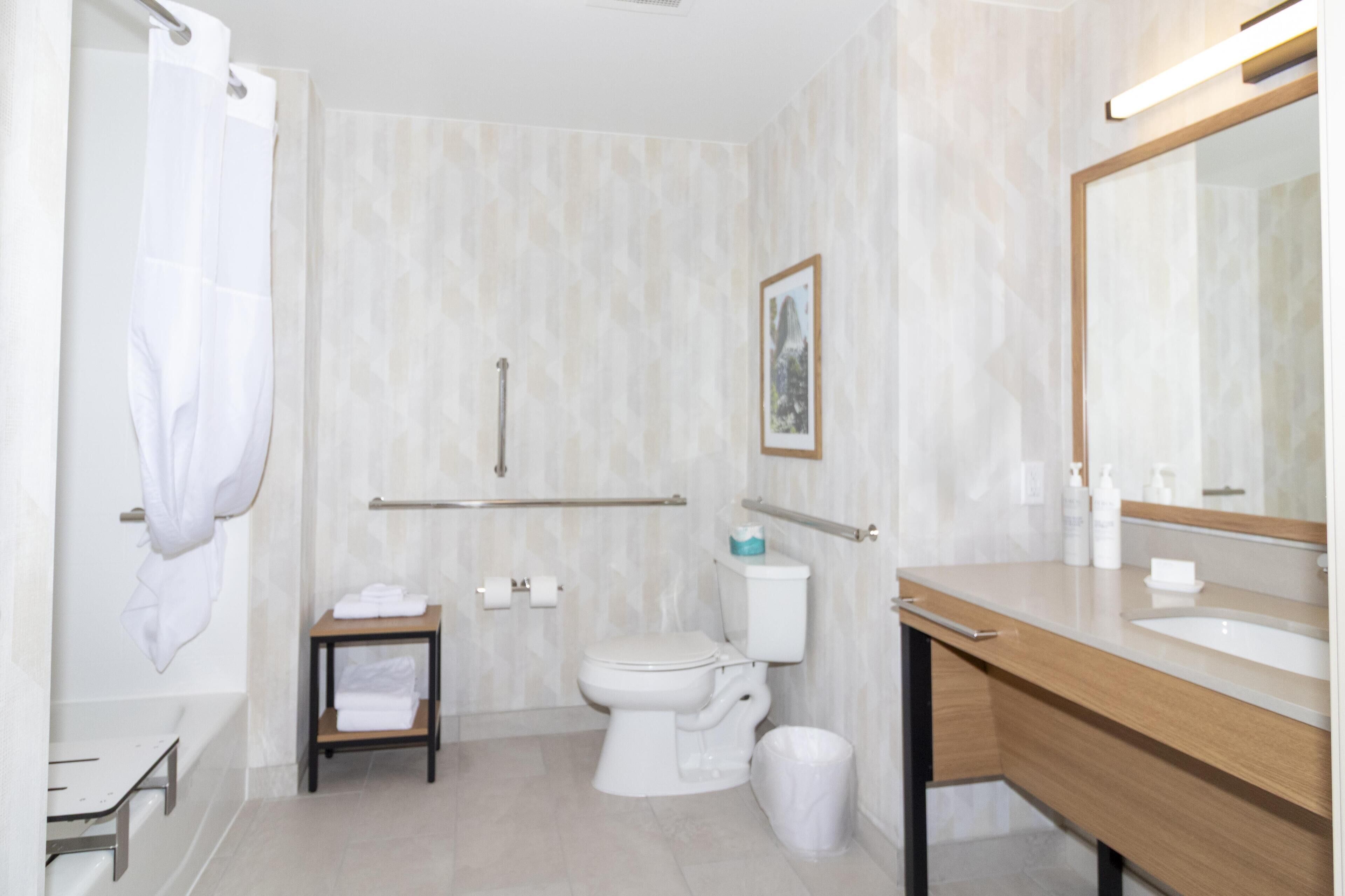 Une salle de bain moderne équipée d’une baignoire, de toilettes, d’un meuble-lavabo et d’un grand miroir.