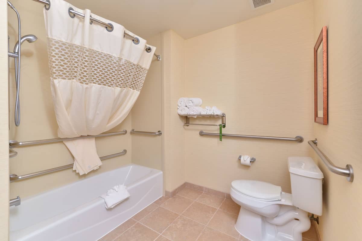 A bathroom with a bathtub, toilet, and shower curtain.